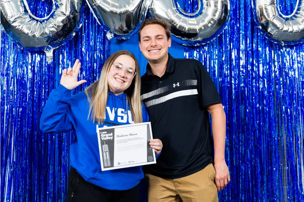 student holds up L for Laker and certificate with fellow student